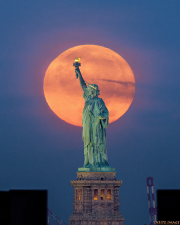 Harvest Moon setting behind the Statue of Liberty